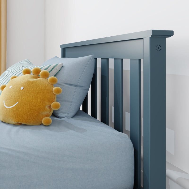 Blue wooden toddler bed headboard with vertical slats, light-blue bedding and striped pillow, yellow sun plush toy in a modern nursery interior
