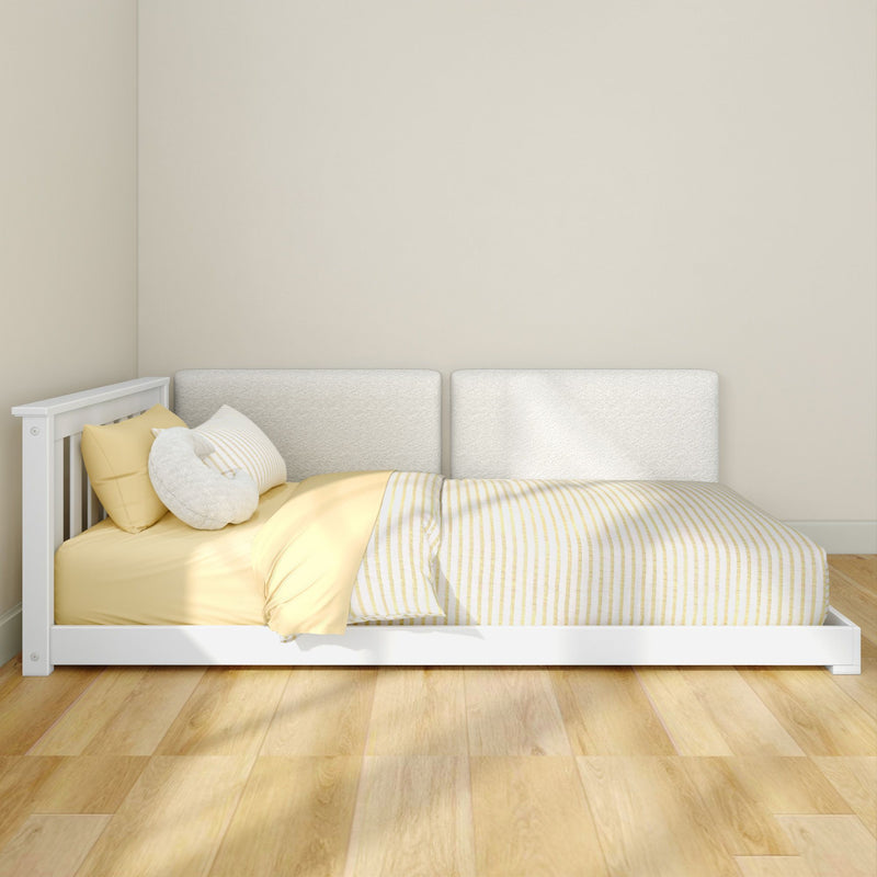Minimalist white low platform bed with yellow-striped bedding and plush pillows on light hardwood floor