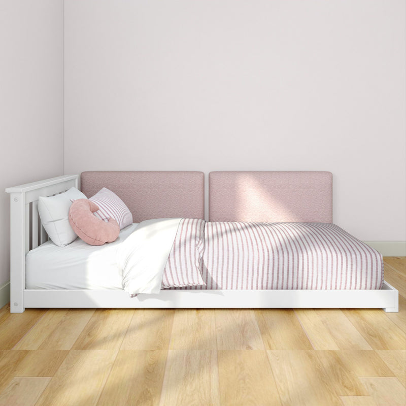 Cozy pink nursery bed with white wooden frame, striped pink-and-white bedding, soft padded headboard panels and hardwood floor
