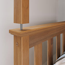 Close-up of solid oak slatted headboard on a wooden bed frame with natural oak finish and visible metal support rod, modern bedroom furniture detail