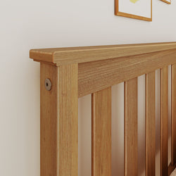 Close-up of solid oak slatted bed headboard with natural finish mounted against a white wall, modern wooden bedroom decor