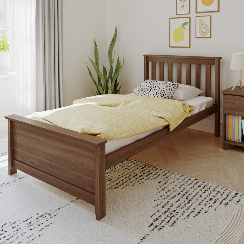 Minimalist wooden single bed with yellow duvet and spotted pillow in a bright modern bedroom with bedside table, indoor plant, and framed fruit prints