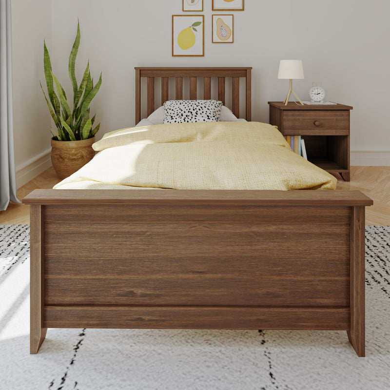 Oak wooden single bed with yellow duvet, black-spotted pillow, bedside table and lamp, and potted snake plant in a minimalist modern bedroom