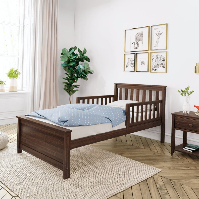 Dark walnut wooden toddler bed with safety rails and blue polka-dot bedding in a bright modern nursery — single kids' bed