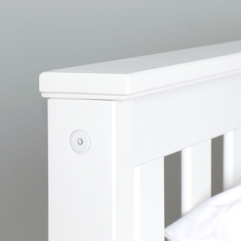 Close-up of white painted wooden crib rail and headboard detail with visible screw cap, modern nursery bed furniture