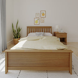 Modern bedroom with wooden bed frame, nightstand, potted plant, and framed wall art for cozy interior design.