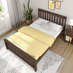 Modern bedroom with wooden bed frame, yellow bedding, and indoor plant for cozy home decor.