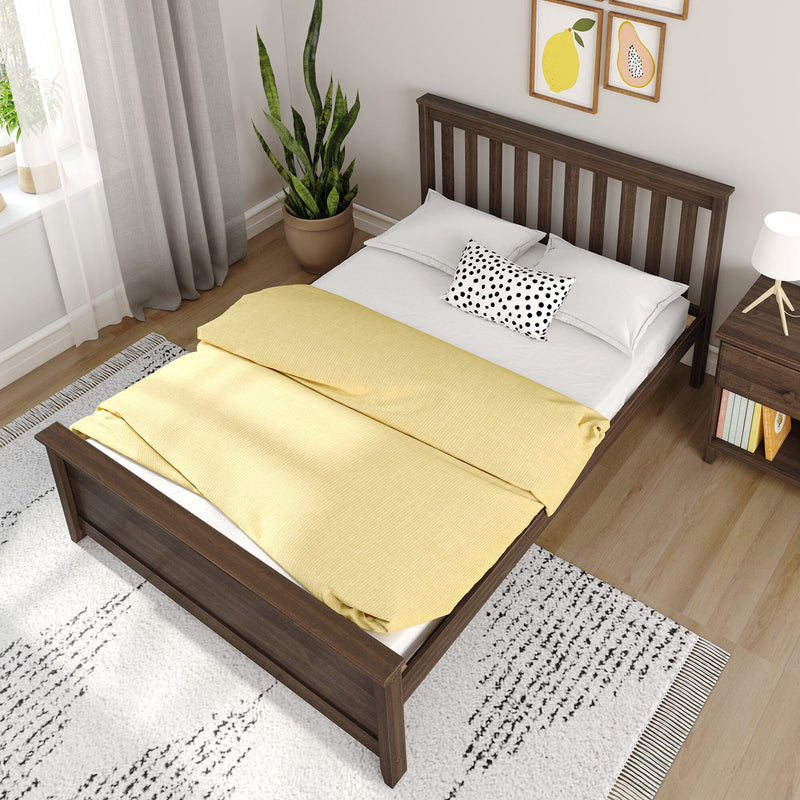 Modern bedroom with dark wood bed, yellow duvet and white pillows, black-dot throw pillow, bedside lamp, potted snake plant and framed fruit art