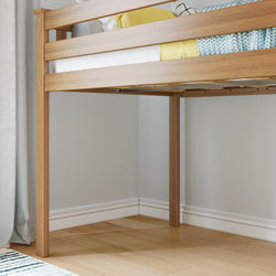 Wooden bunk bed corner with yellow and blue pillows on a neatly made bed, showcasing modern bedroom decor.