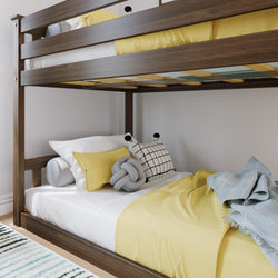 Modern wooden bunk bed with yellow bedding, decorative pillows and light blue throw in a kids' bedroom
