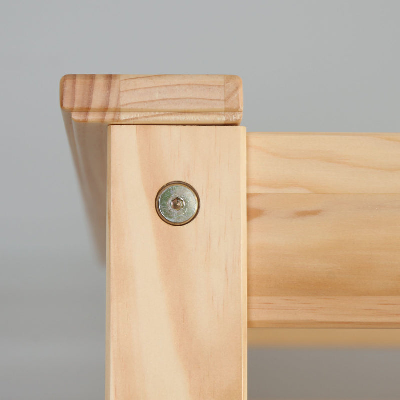 Close-up of light pine furniture corner joint with exposed hex bolt and visible wood grain, furniture assembly detail