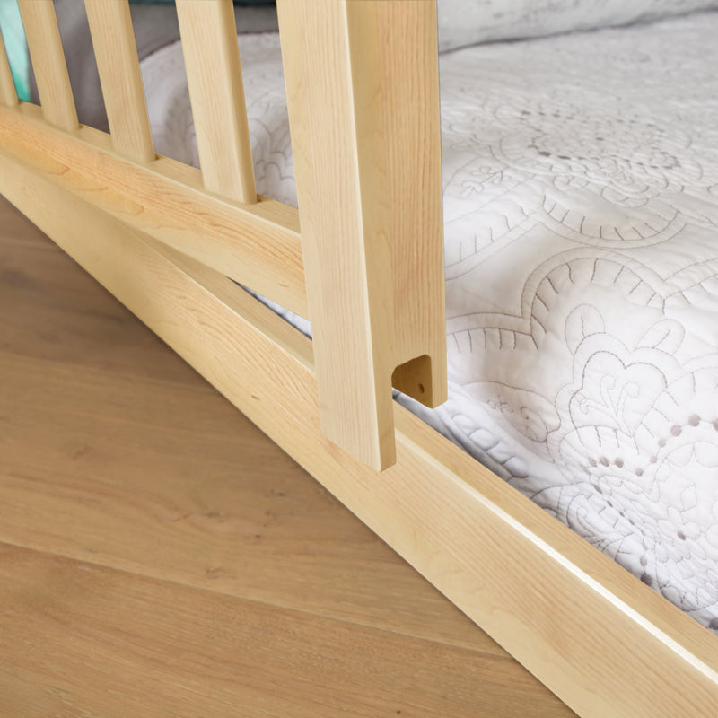 Close-up of natural oak wooden bed frame slats and rail with white quilted mattress cover on hardwood floor