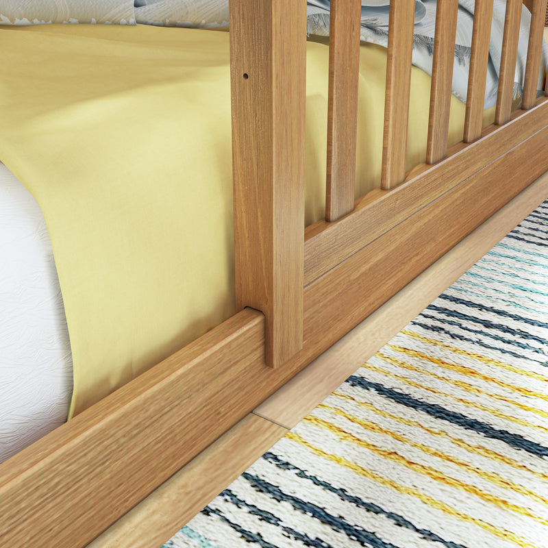Close-up of natural wood slatted bed frame with yellow fitted sheet and striped area rug