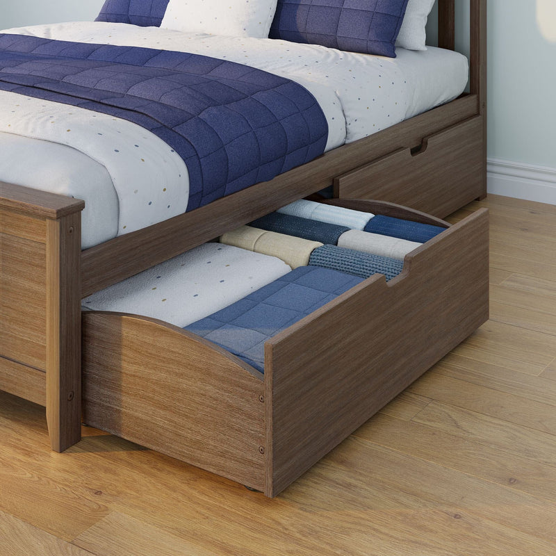 Wood platform bed with pull-out under-bed storage drawer filled with folded blue and beige blankets on hardwood floor
