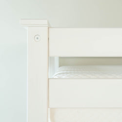 White bunk bed frame with comfortable mattress in minimalistic bedroom setting.