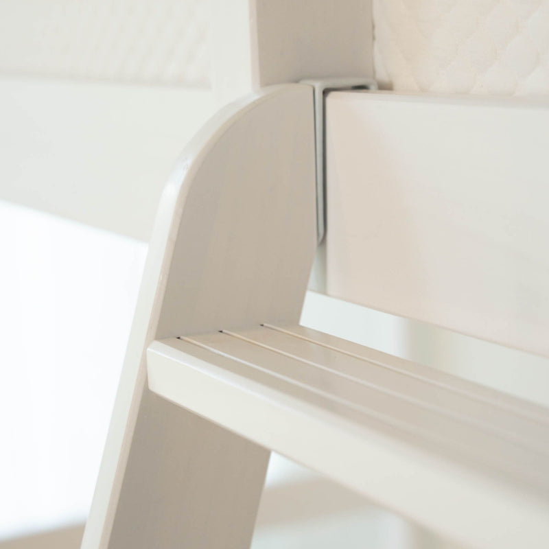 Close-up of a white slatted wooden chair with curved back and light wood finish, minimalist modern home furniture detail