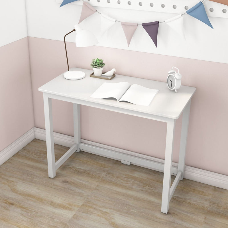 Minimalist white writing desk in a pastel pink corner with an open notebook, white desk lamp, succulent planter, alarm clock and bunting flags on light wood floor