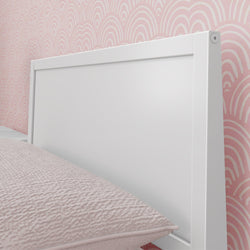White headboard with pink textured pillow and retro pink wallpaper design.