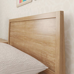 Wooden bed headboard with natural finish in a modern bedroom setting.