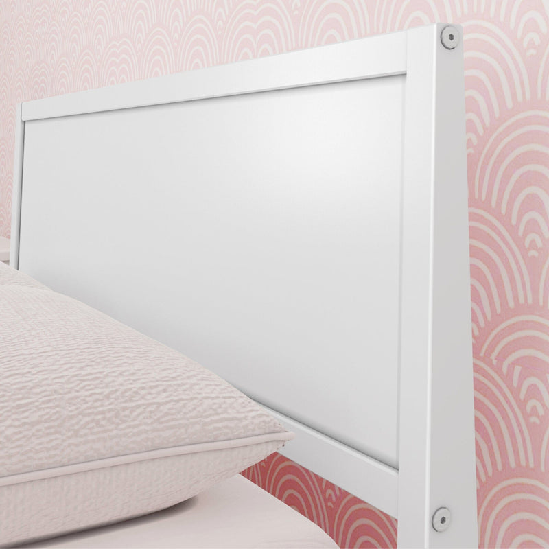 Close-up of white wooden headboard with pale pink textured bedding and pink scallop wallpaper background, modern bedroom decor