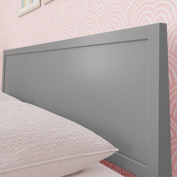 Gray modern bed headboard against pink patterned wallpaper in a cozy bedroom setting.