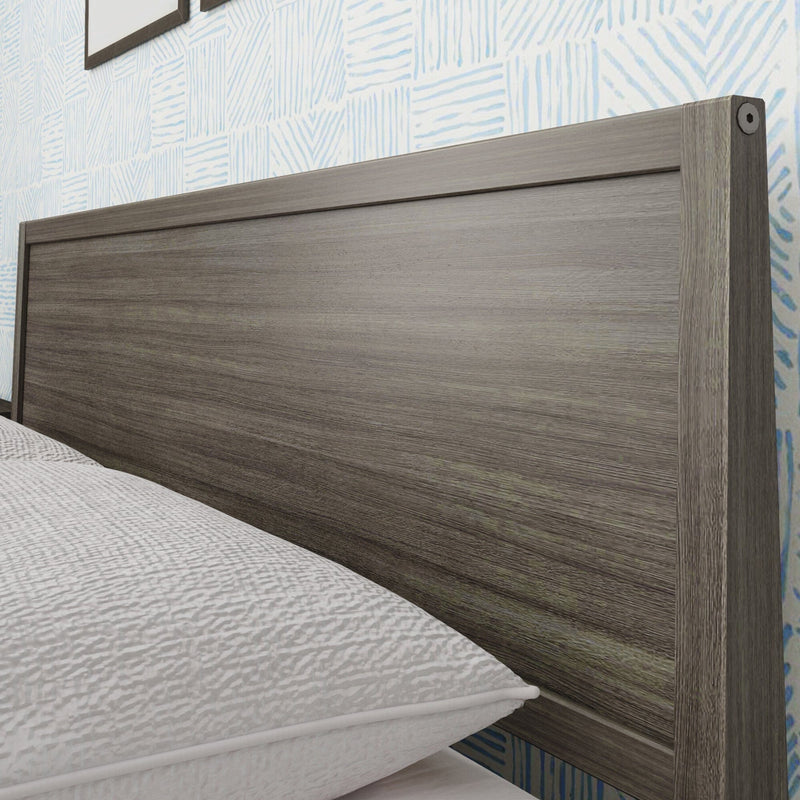Close-up of modern gray wooden headboard with textured blue wallpaper and white quilted bedding in a contemporary bedroom