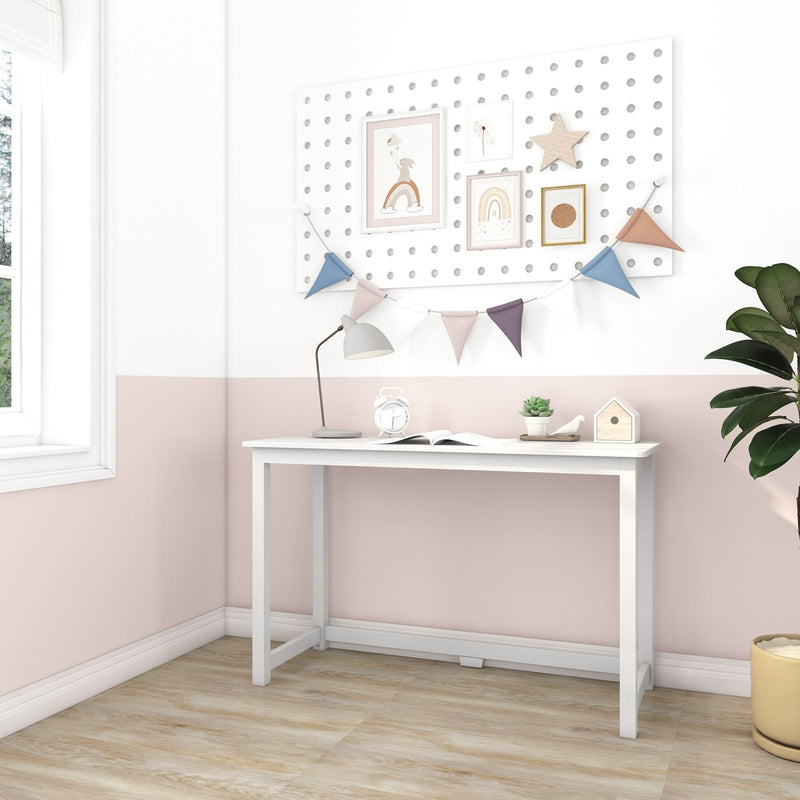 Kids desk and nursery decor: pastel pink and white study nook with white pegboard wall, framed prints, pastel bunting, desk lamp, alarm clock and succulent.