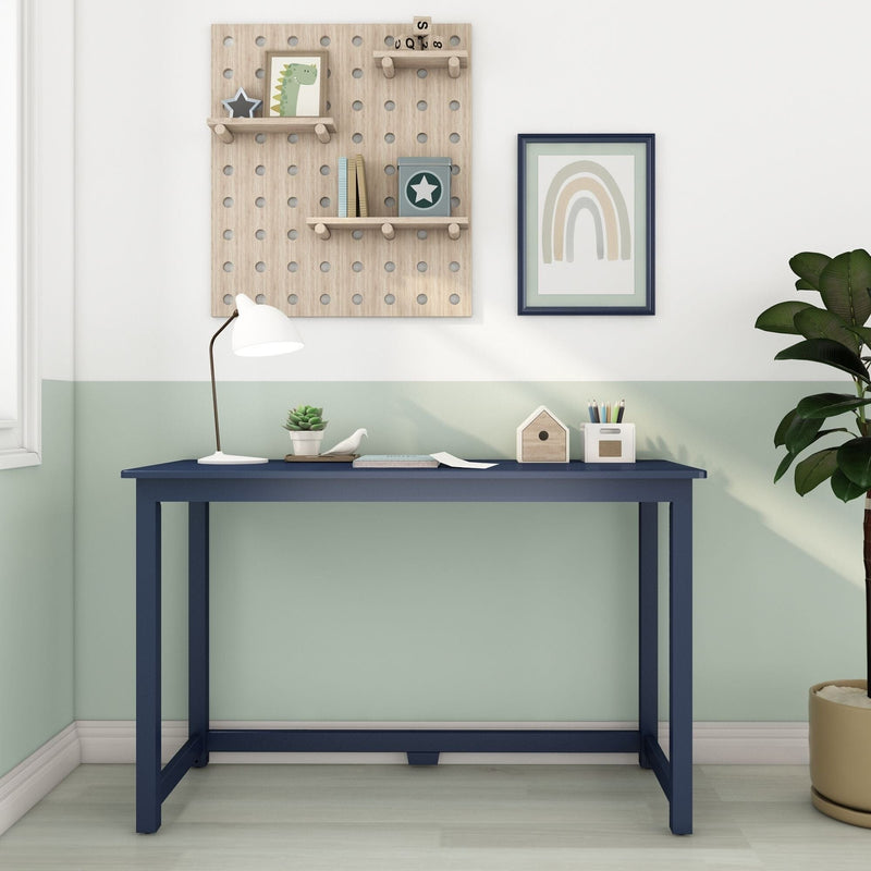 Modern navy blue children's study desk in pastel green kids' room with white desk lamp, wooden pegboard shelves, rainbow wall art, succulent and pencil holder