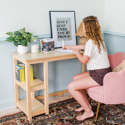 Young woman writing at a wooden desk with motivational quote, home office decor.