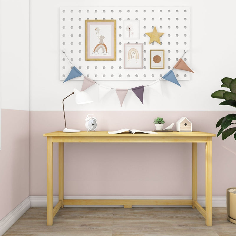 Scandinavian-style children's study nook with light wood desk, white desk lamp, alarm clock, open book, succulent, birdhouse and pegboard wall art with pastel rainbow prints and bunting