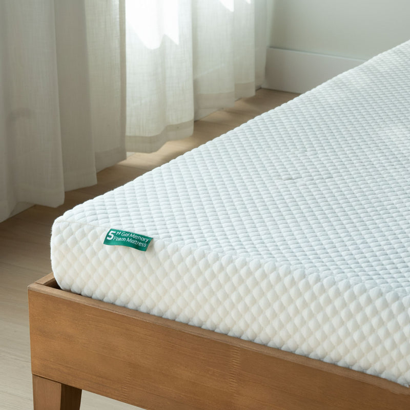 Close-up of white quilted memory foam mattress with textured cover on wooden platform bed frame in bright minimalist bedroom