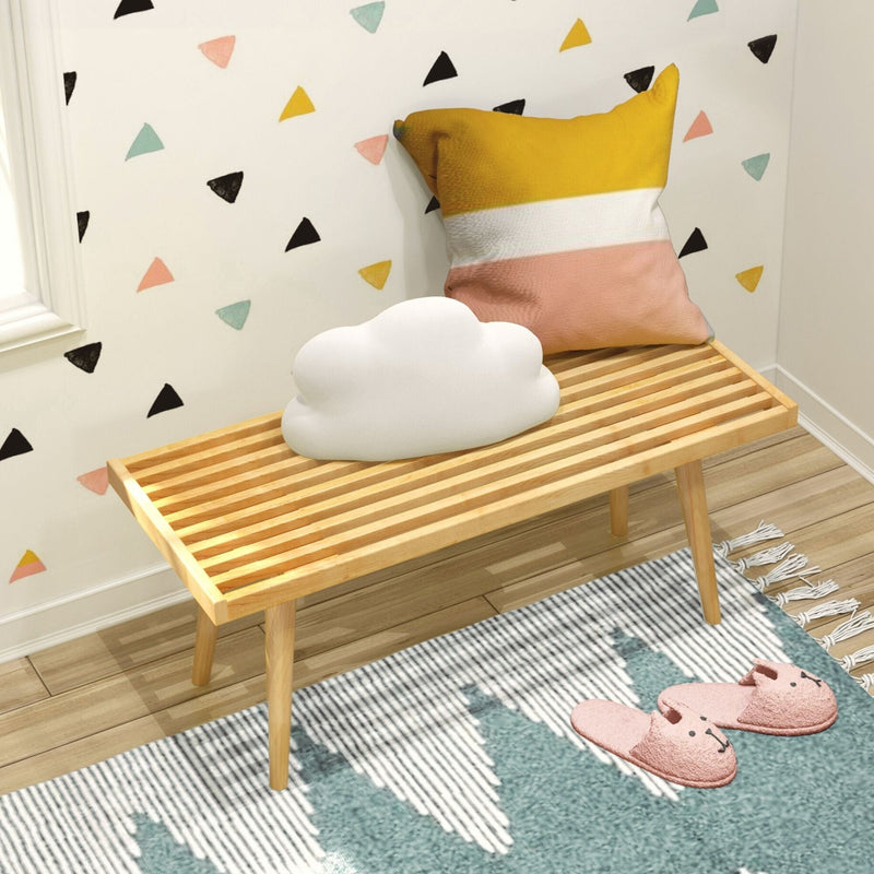 Cozy bedroom corner with a striped wooden bench, yellow and pink pillow, cloud-shaped cushion, and playful wall decor, perfect for a modern kids' room.