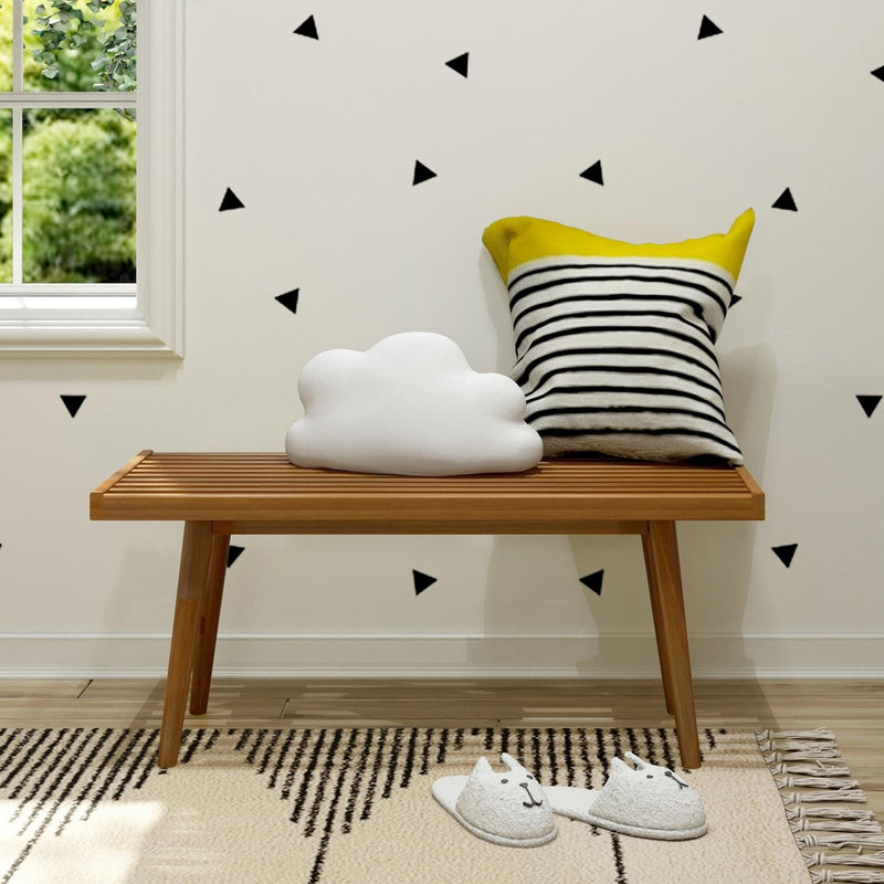 Stylish minimalist interior with wooden bench, cloud cushion, striped pillow, and cat slippers on patterned rug.