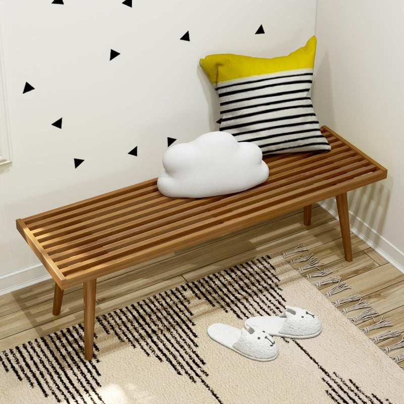 Scandinavian nursery decor: wooden slatted bench with cloud cushion, yellow-and-black striped pillow, black triangle wall decals, patterned rug and kids slippers