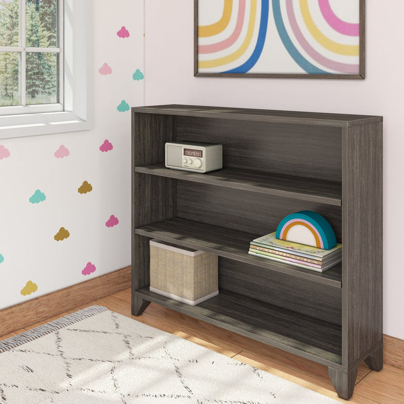 Modern dark wood bookshelf in children's room with toys and books on wooden floor near colorful wall decoration.