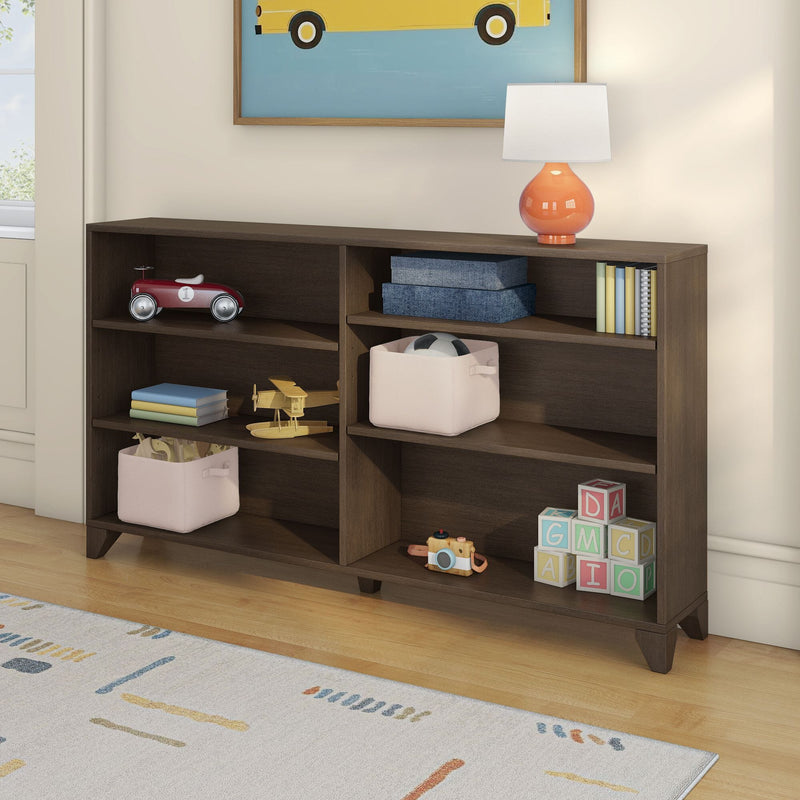 Dark wood kids bookshelf and nursery storage shelf with pink fabric bins, orange lamp, wooden airplane, red toy car and alphabet blocks on hardwood floor