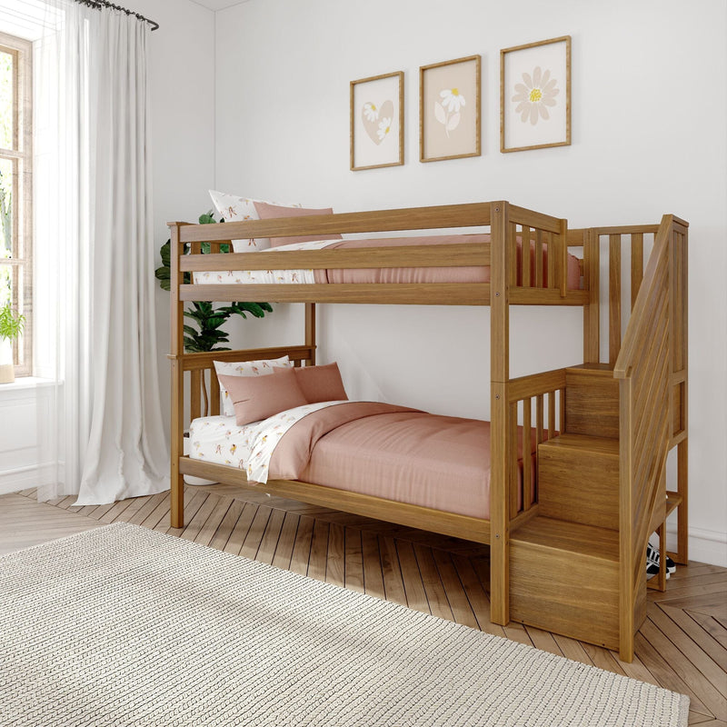Natural wood twin-over-twin bunk bed with staircase, pink bedding and floral pillows in a bright modern kids' bedroom with framed wall art