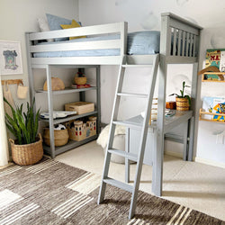 Gray loft bed with ladder and desk in a kid's room with decorative shelves and plants.