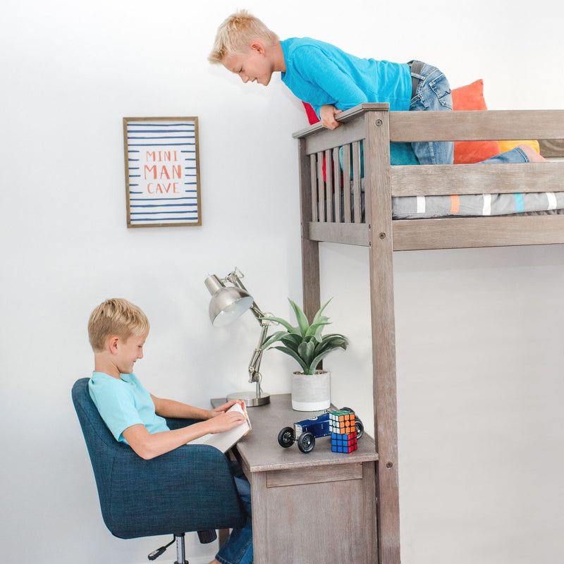 Child's loft bed with built-in desk in modern kids bedroom, boy reading at desk under a lamp with toy car, Rubik's Cube, potted plant and framed "Mini Man Cave" wall art