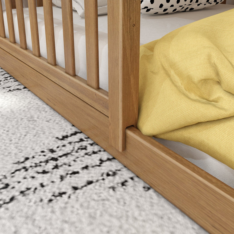 Close-up of natural oak slatted wooden bed frame and platform with white mattress, yellow duvet and black-and-white textured rug in a modern bedroom