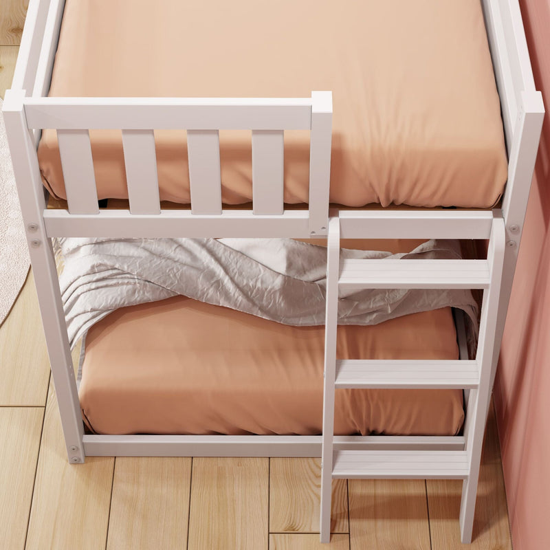 Top-down view of white wooden bunk bed with ladder, peach fitted sheets and beige blanket on lower bunk on hardwood floor in children's bedroom