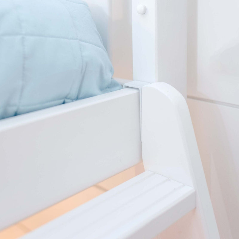 Close-up of white wooden bed frame and safety rail with light blue quilted bedding in a minimalist bedroom