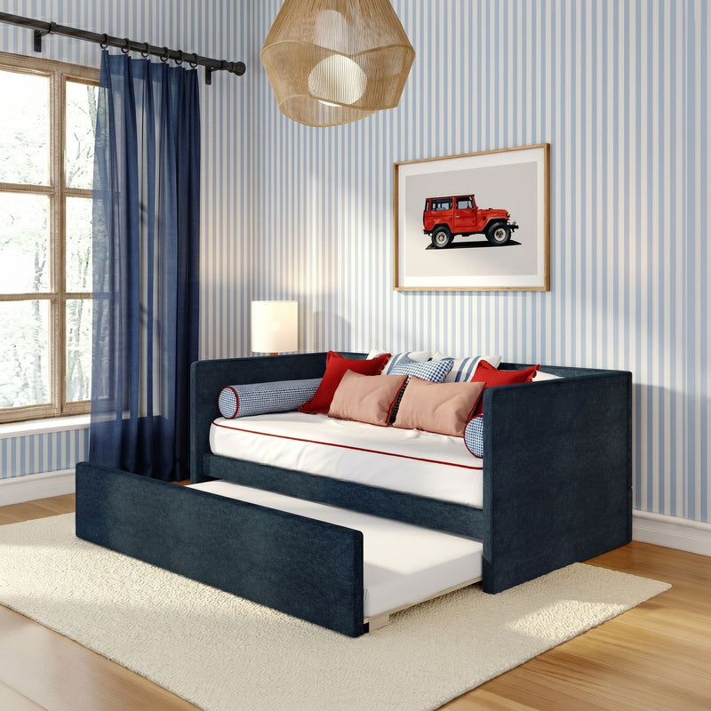 Kids bedroom with navy blue daybed and pull-out trundle, striped blue wallpaper, navy curtains, red accent pillows, wicker pendant light and framed red vintage SUV art