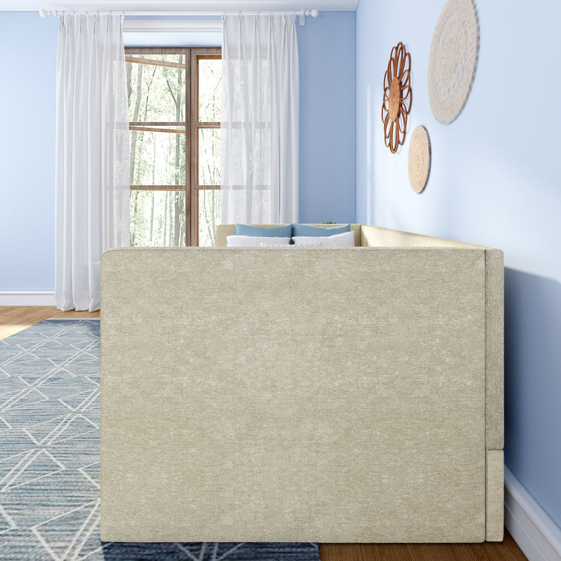 Bright living room with beige sofa back, sheer white curtains over a wooden window, light blue walls, woven rattan wall decor, blue geometric rug, and coordinating blue throw pillows.