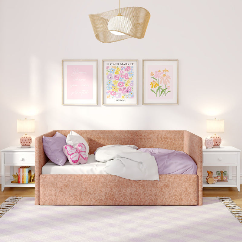 Pastel pink girls' bedroom with upholstered pink daybed, butterfly pillow and lavender bedding, framed floral wall art, rattan pendant light and matching bedside lamps
