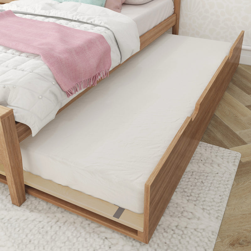 Wooden trundle bed with underbed pull-out mattress, white quilted bedding and pink throw blanket in a space-saving kids' bedroom