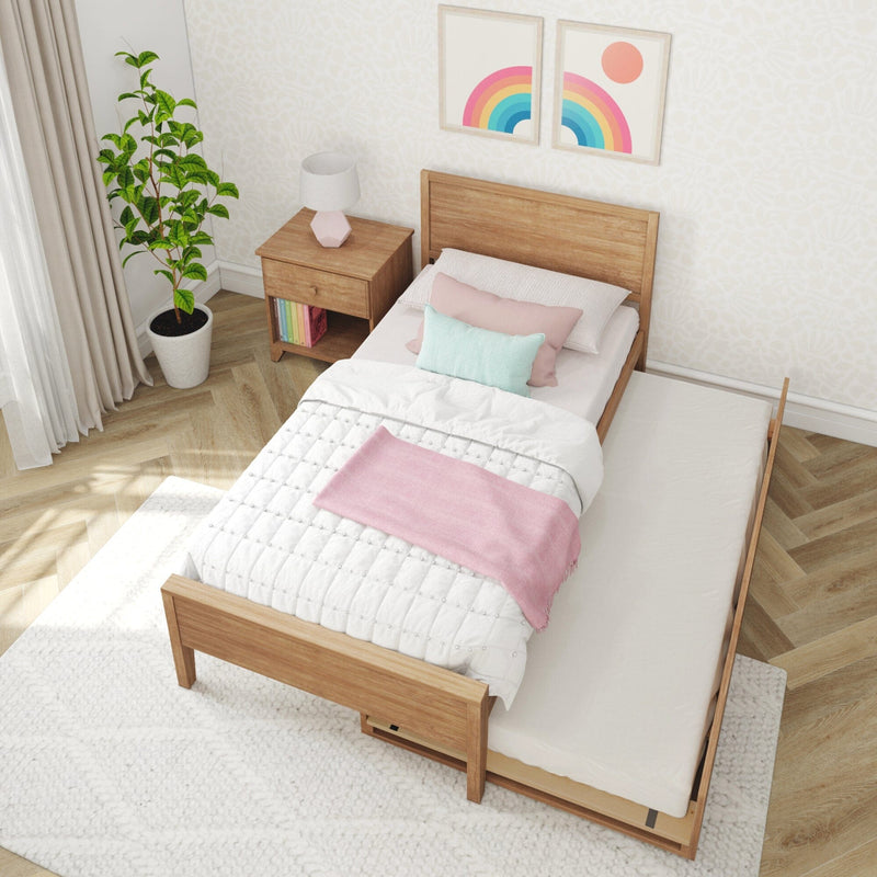 Bright minimalist bedroom with wooden twin bed, pastel pink and mint bedding, wooden nightstand, potted plant, rainbow wall art