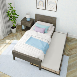 Modern bedroom with stylish trundle bed, white comforter, pastel pillows, and a bedside table with a lamp, showcasing cozy and functional interior design.