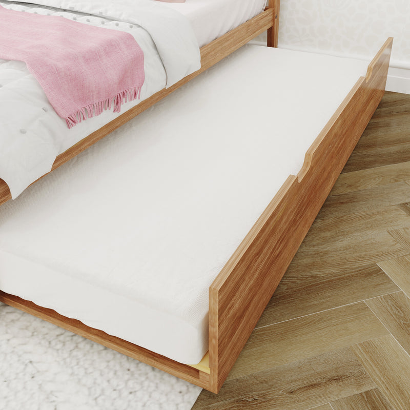 Light wood trundle bed with white mattress tucked under a bed dressed in white linens and a pink fringed throw on hardwood flooring