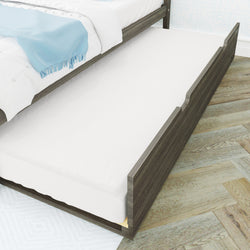 Wooden pull-out trundle bed with white mattress and light blue throw under a dark wood bed frame, twin under-bed storage trundle for guest sleeping and extra bedding on hardwood floor